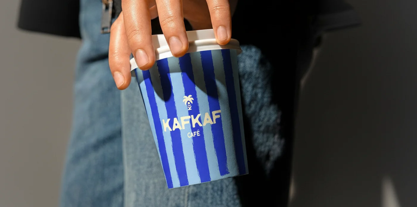 Un gobelet rayé Kafkaf tenu du bout des doigts