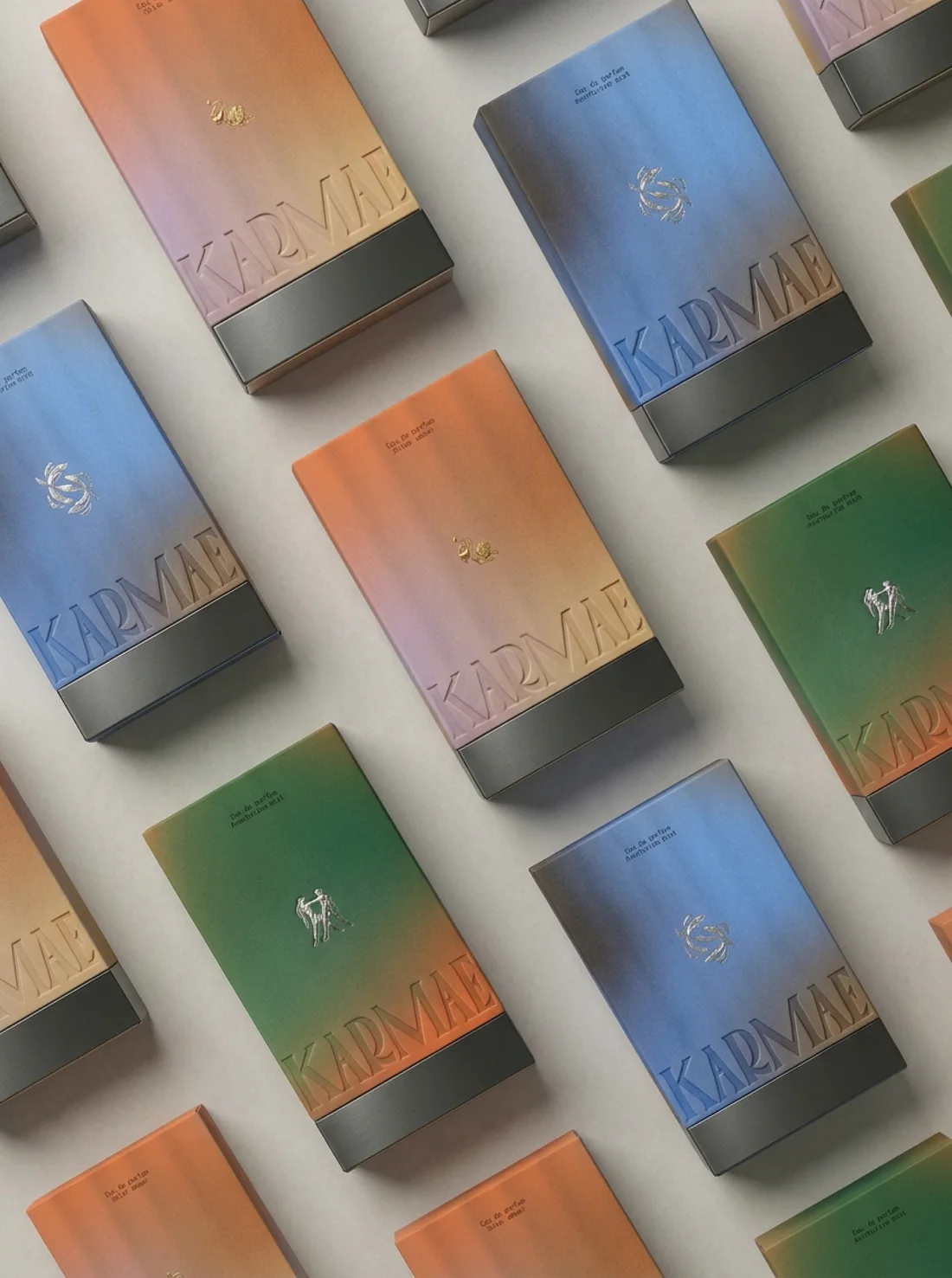 Coffrets Karmae en dégradés orange, bleu et vert, alignés en diagonale, logotype gaufré et socle en métal brossé