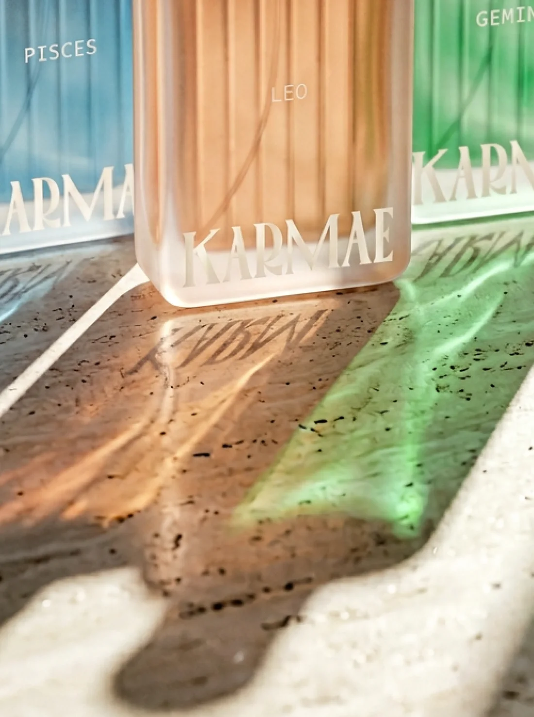 Flacons Pisces, Leo et Gemini projetant des ombres colorées sur la pierre