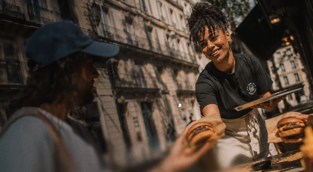 Une serveuse apporte des burgers en terrasse