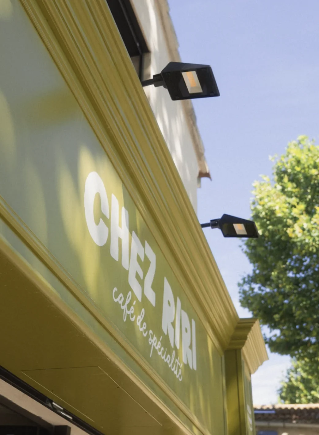Le lettrage « Chez Riri » vu en contre-plongée, au soleil