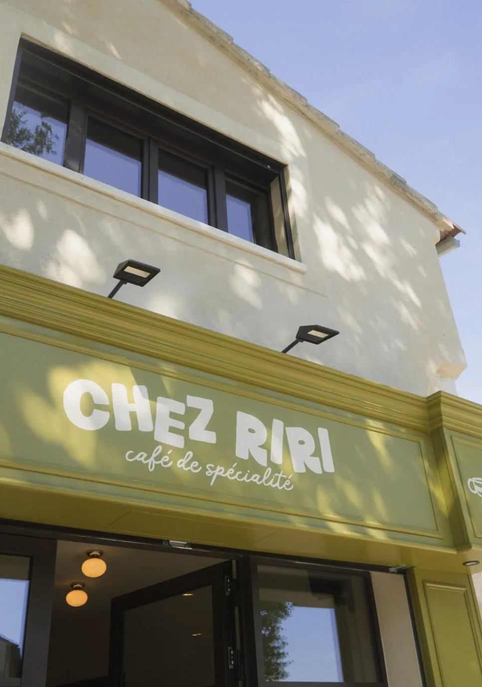 L'enseigne terminée : « Chez Riri » en grandes lettres blanches et « café de spécialité » en script