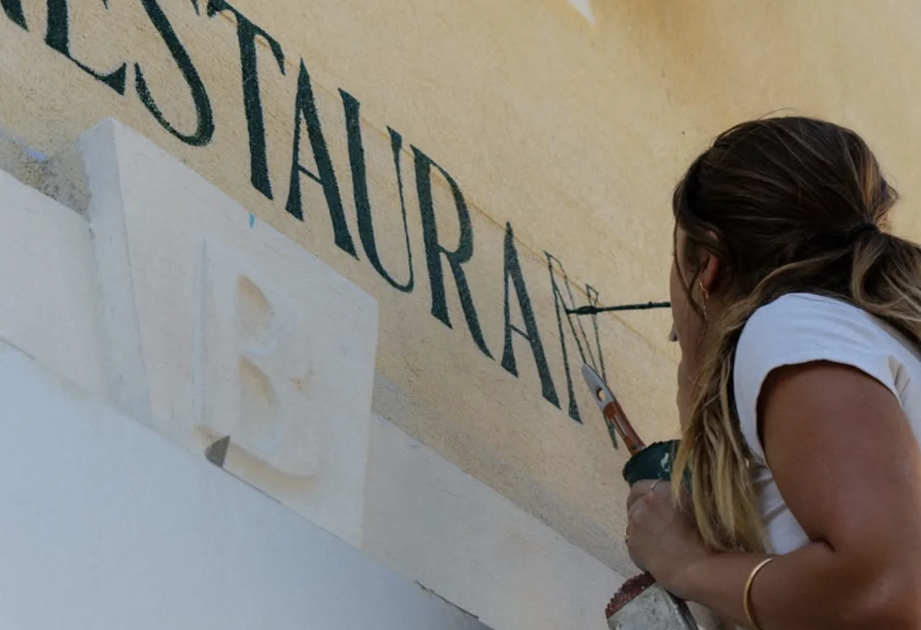 Iona peint le T final de « Restaurant », pot de peinture à la main